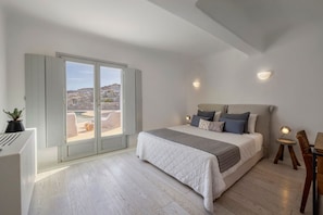 Ein Schlafzimmer mit einem großen Bett, einer Schiebetür zu einem Balkon und einem kleinen Tisch mit einer Lampe.
