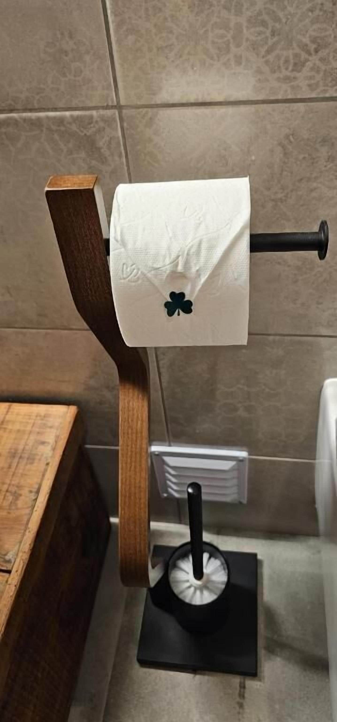 A toilet paper holder with a wooden design and a black base, mounted on a tiled wall.