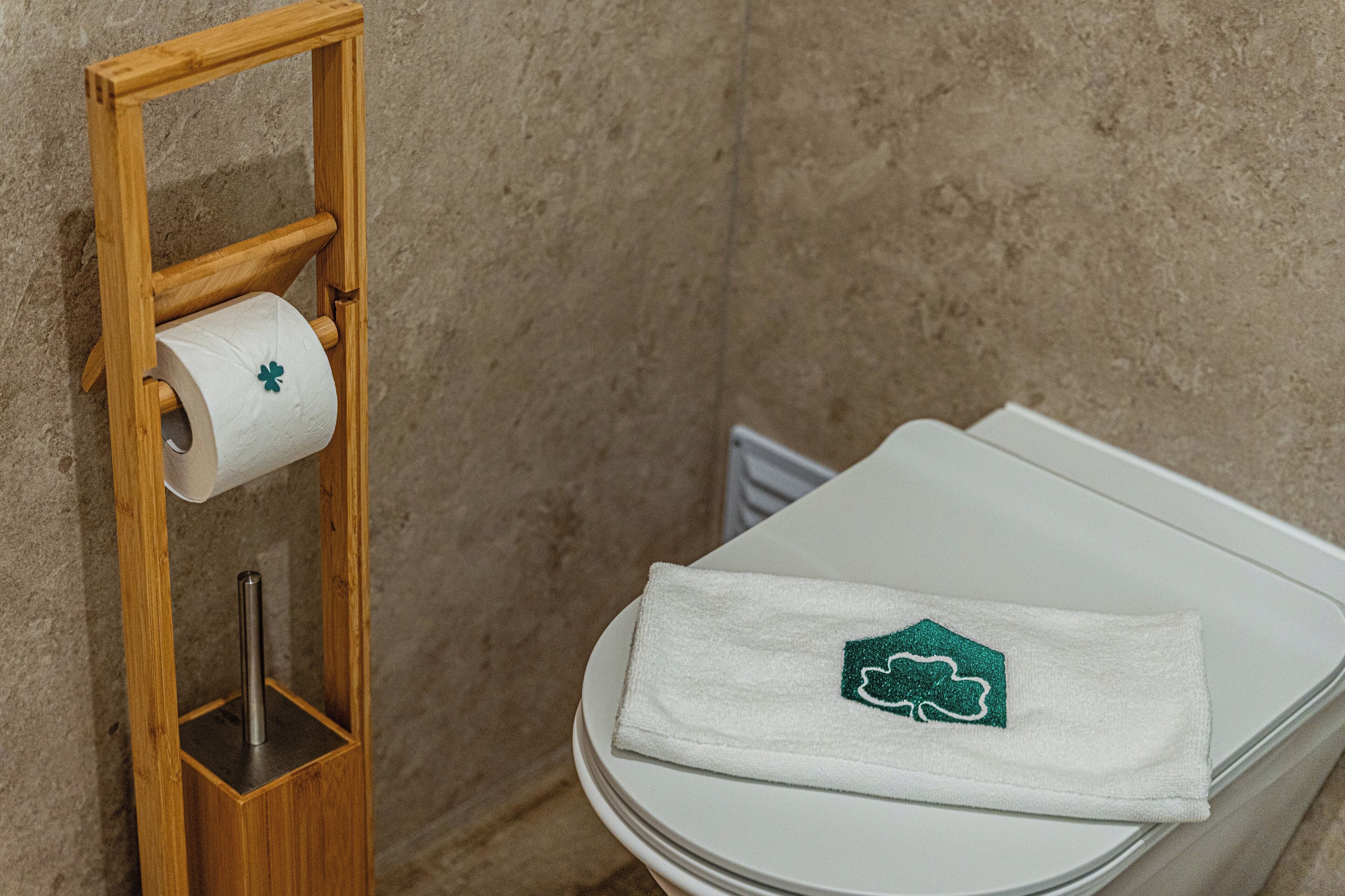 A toilet with a white seat and a towel with a shamrock design.