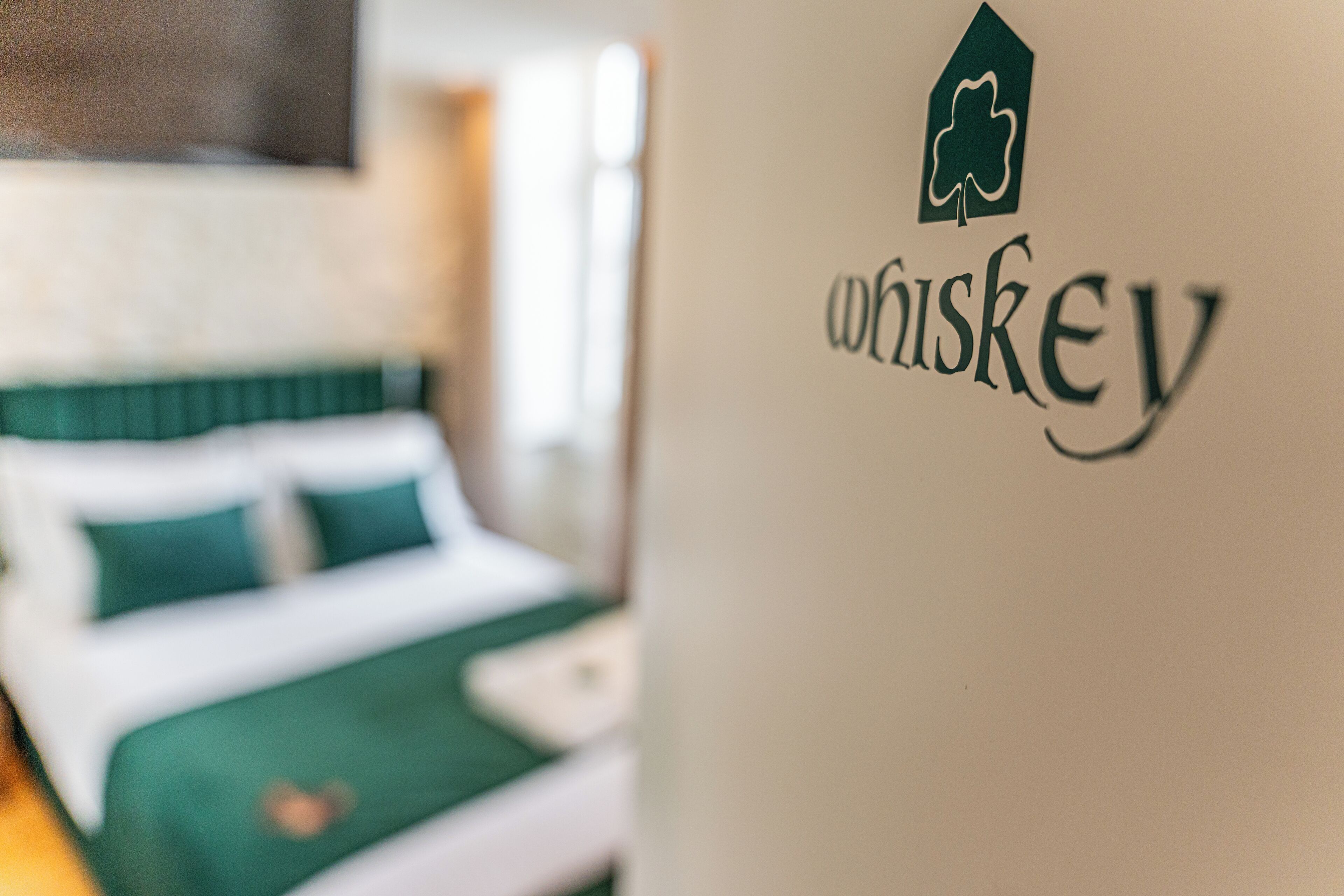 Ein Bett mit grüner Bettwäsche und eine Wand mit einem Whiskey-Logo.