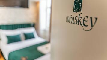Ein Bett mit grüner Bettwäsche und eine Wand mit einem Whiskey-Logo.