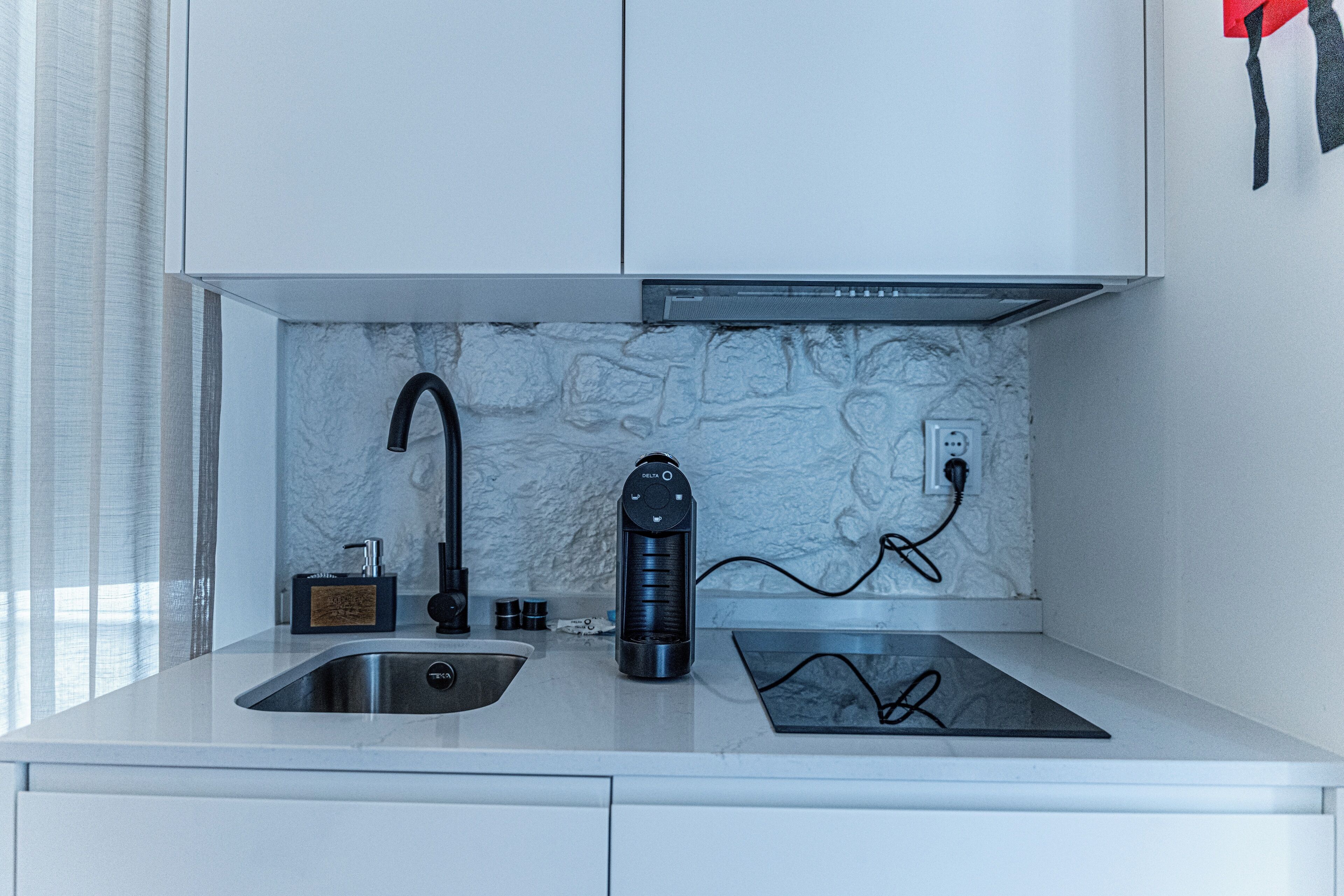 A modern kitchen with a built-in stove, a sink, and a marble backsplash.