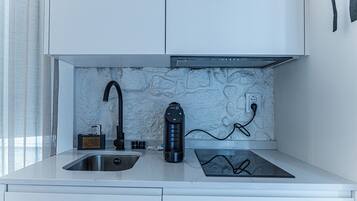 A modern kitchen with a built-in stove, a sink, and a marble backsplash.