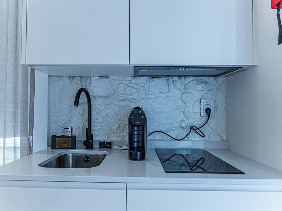 A modern kitchen with a built-in stove, a sink, and a marble backsplash.