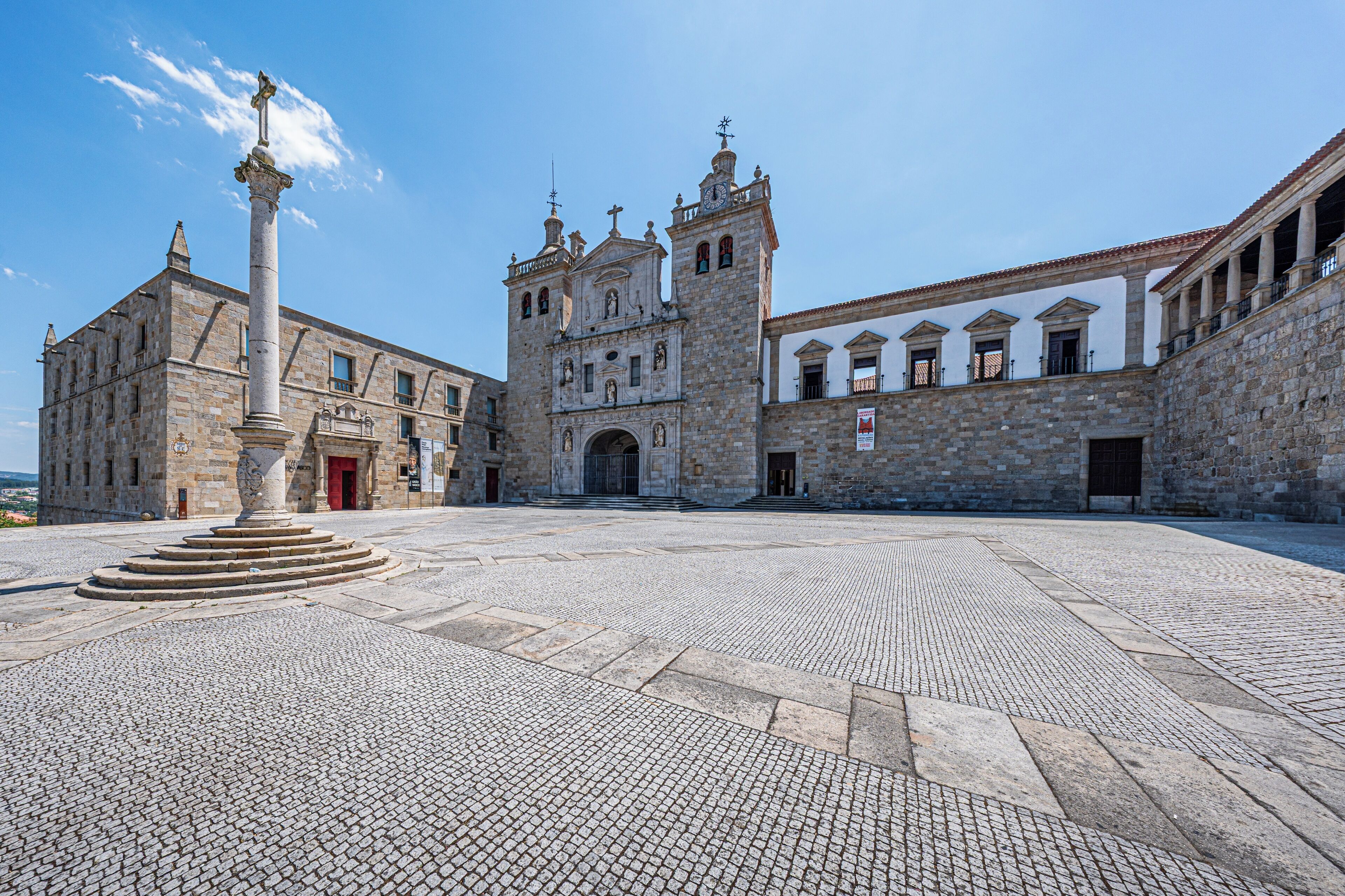 A historic building with a central courtyard, a prominent column, and a clock tower.