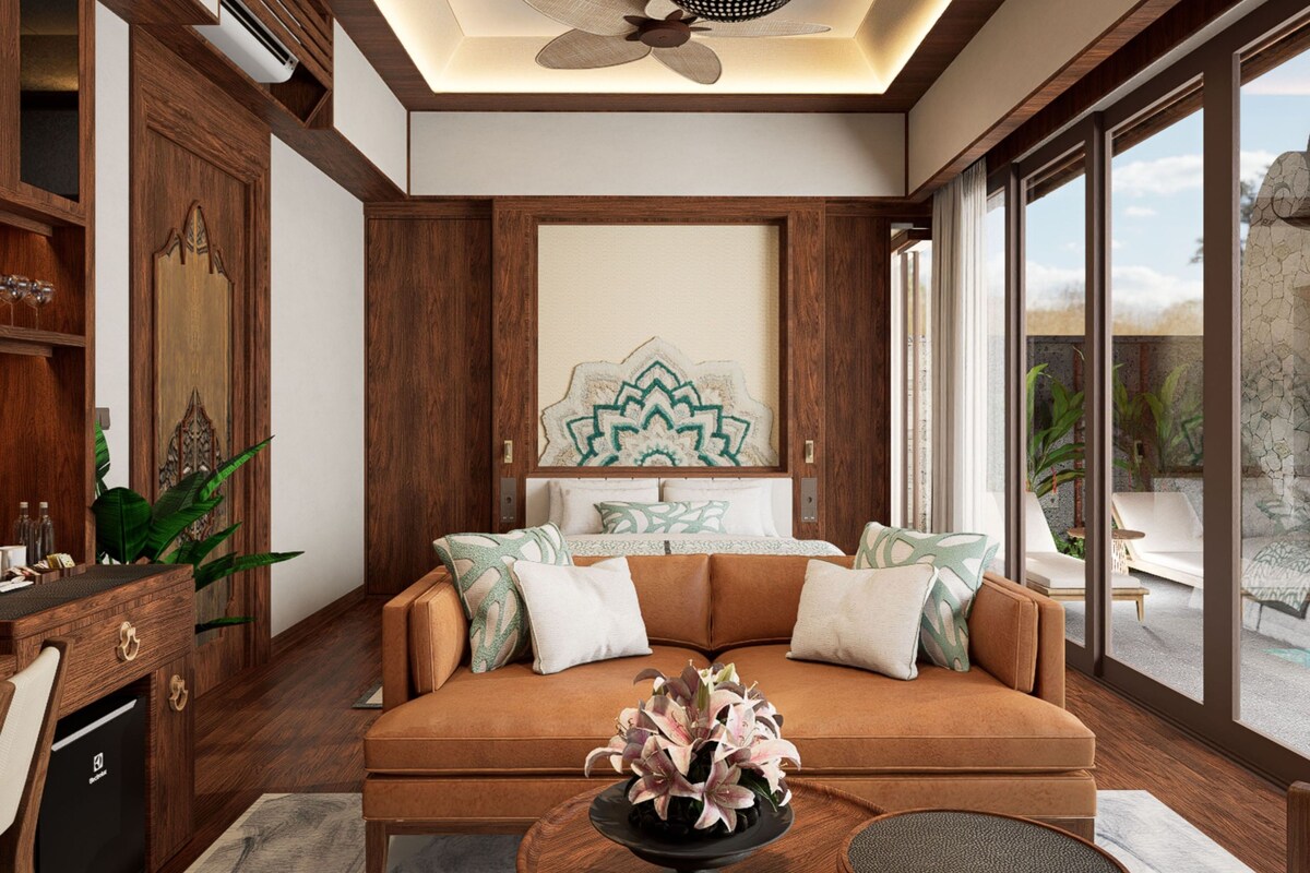 A modern living room with a sofa, decorative pillows, a coffee table with flowers, and a large window offering a view of the outdoors.