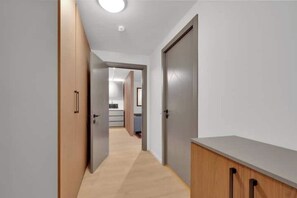 A hallway with wooden cabinets and a kitchenette in the background. - Modern city center apartment with sunny balcony (Oslo)