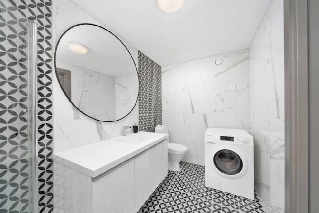 Et moderne badeværelse med en hvid vask, toilet og vaskemaskine.