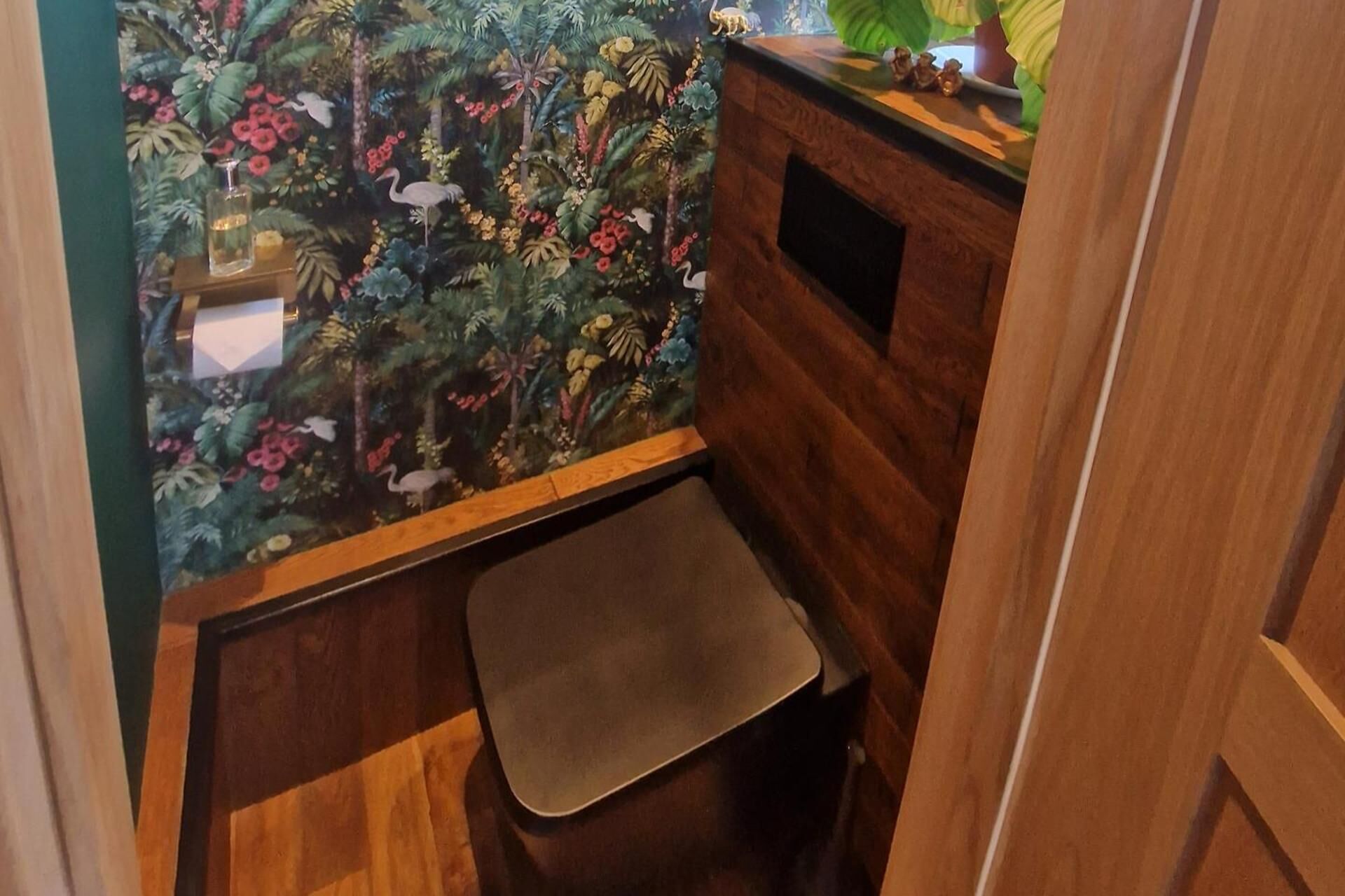 Ett litet badrum med ett handfat i trä, en spegel och en duschhörna med duschdraperi.
