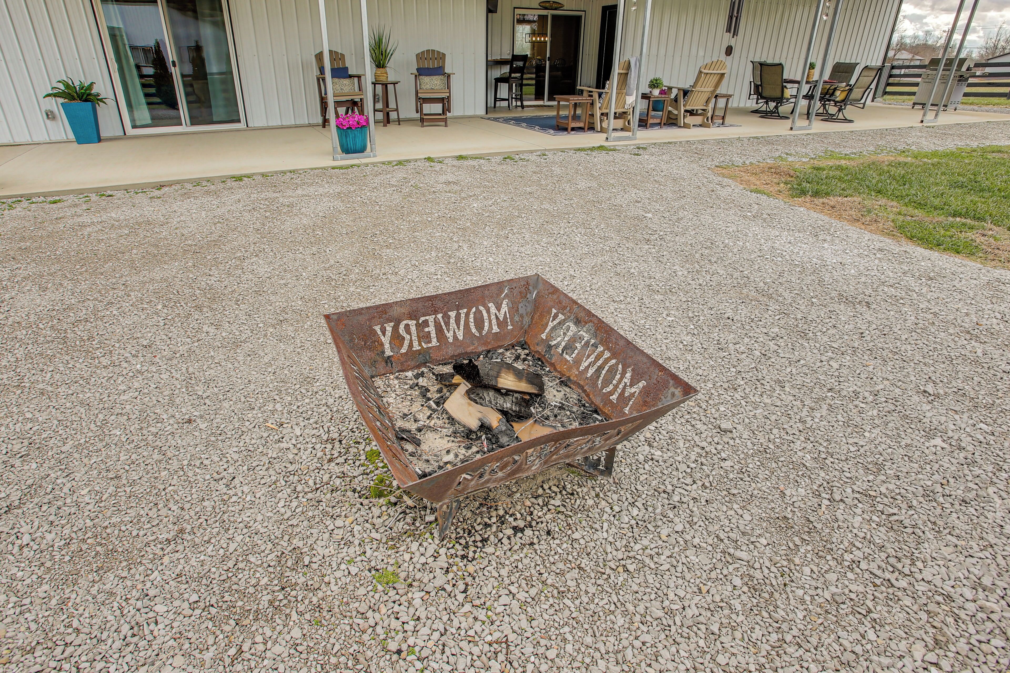 A metal fire pit with the words "MOMENT WOMEN" on it, surrounded by gravel.