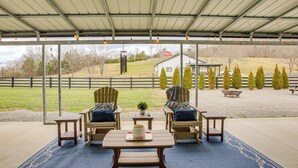 An outdoor patio with wooden furniture, a table with a decorative item, and a view of a farm and trees. - Spacious Patio & Yard! Family Home in Byrdstown (Byrdstown)