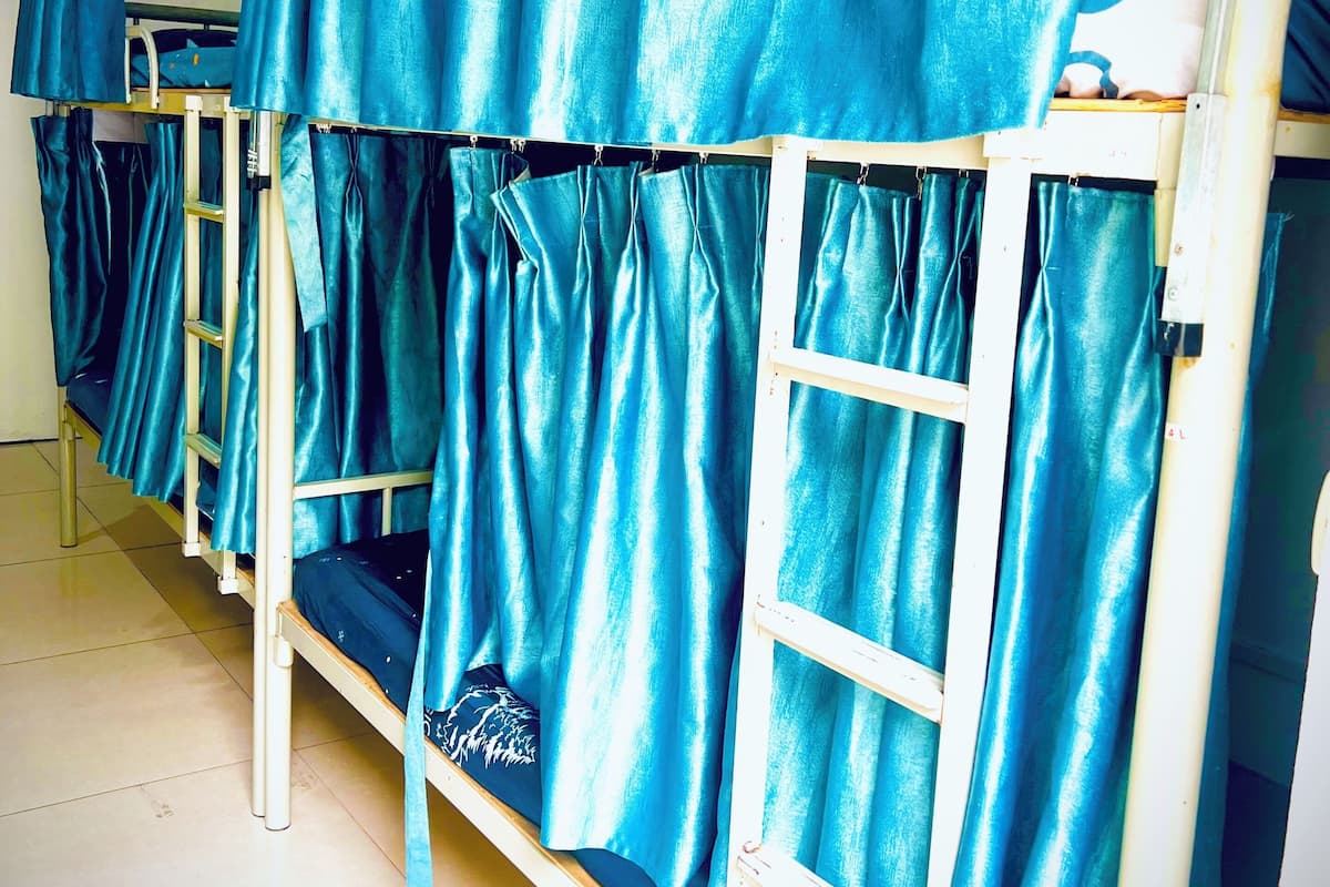 Letto a castello con tende, una scala e pavimento piastrellato.