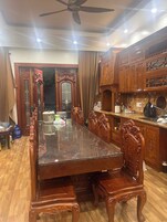 Uma área de jantar com uma grande mesa de madeira e cadeiras combinando, um ventilador de teto e armários de madeira com portas de vidro.