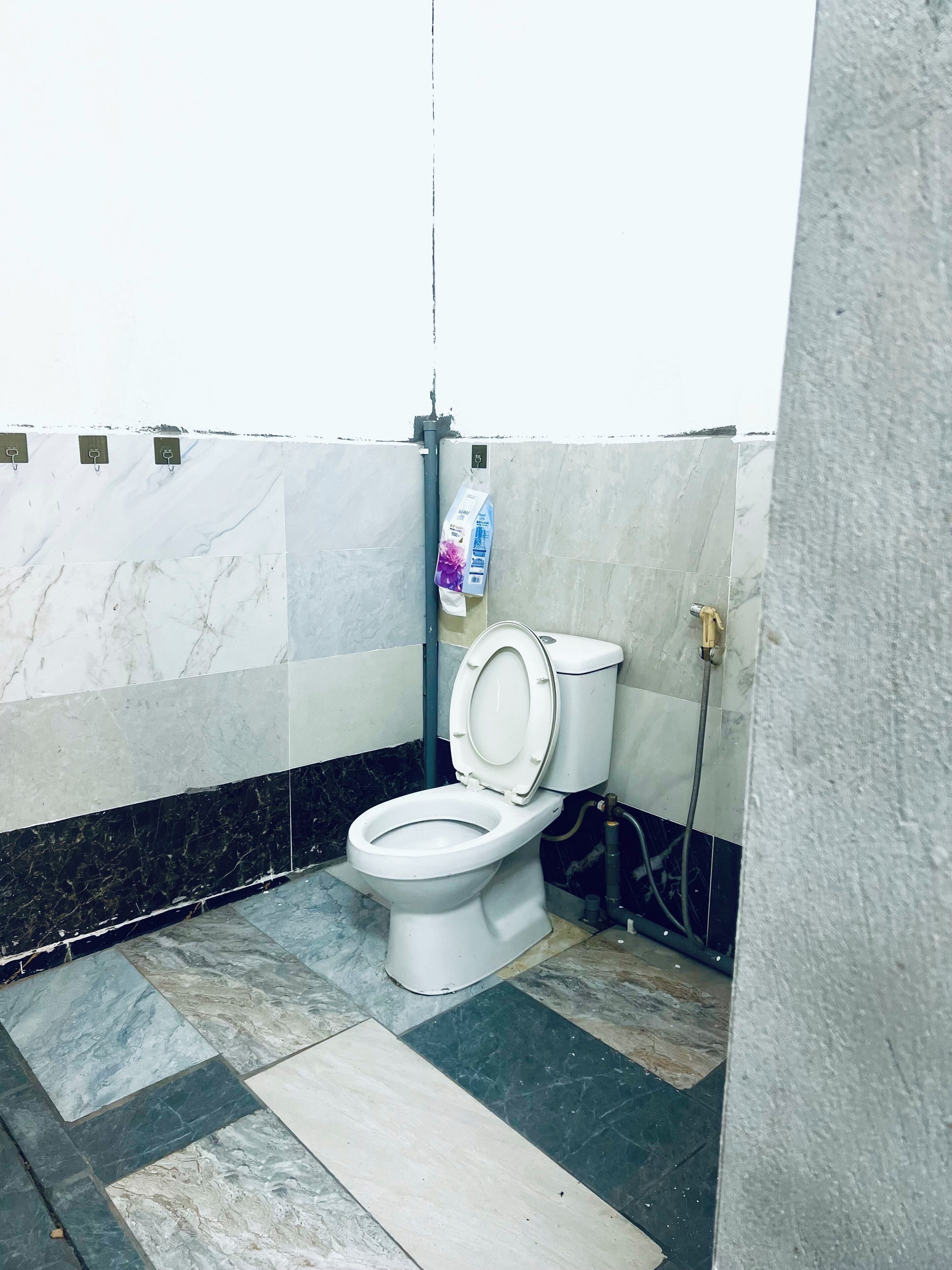 Ein Badezimmer mit Toilette, Marmorfliesen und einem Handdesinfektionsspender.