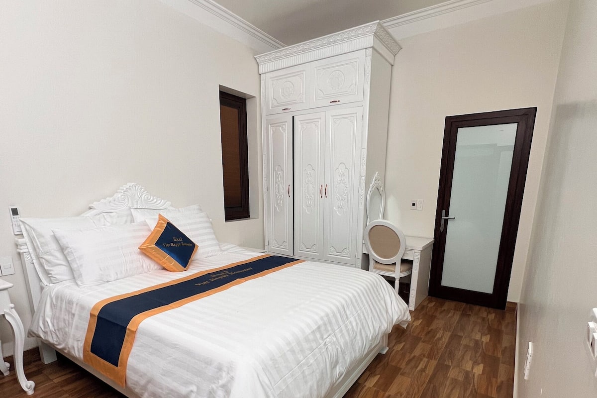 Una camera da letto con un letto grande, un armadio, un comodino e una porta.