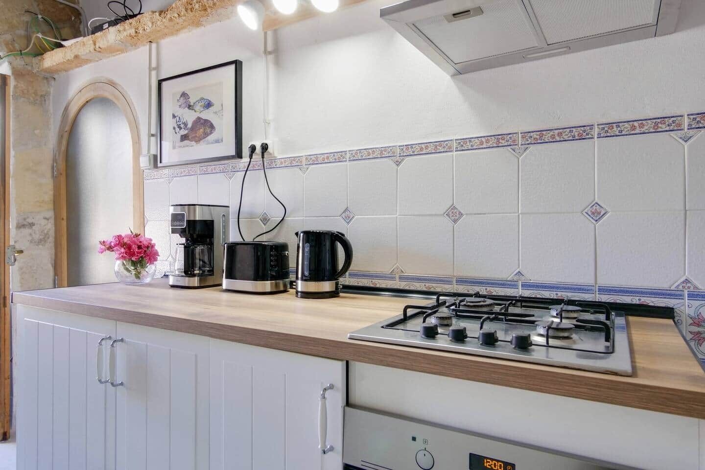 A kitchen with a gas stove, coffee maker, and kettle on the counter.