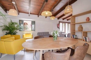 A modern living room with a round wooden table, yellow and grey sofas, wicker lamps, and a bookshelf. - Caragol - Yoga, Nature, AC, XXL Pool (AG/6) (Manacor)