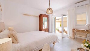 Ein Schlafzimmer mit Bett, Nachttisch, Lampe, Holzschrank und Schreibtisch mit Stuhl.