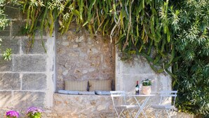 A stone wall with a built-in bench, a small table with a bottle and glass, and two potted plants. - Caragol 2 - Nature, XXL Pool, Yoga, AC (AG/6) (Manacor)