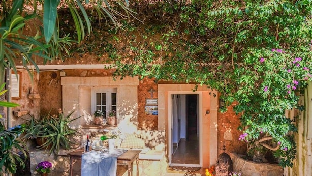 A rustic outdoor seating area with a table and chairs, surrounded by potted plants and a stone wall. - Caragol 2 - Nature, XXL Pool, Yoga, AC (AG/6) (Manacor)