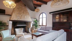 A cozy living room with a stone fireplace, comfortable seating, and hanging wicker lamps. - Caragol 2 - Nature, XXL Pool, Yoga, AC (AG/6) (Manacor)