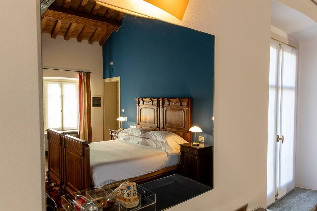 Una camera da letto con un letto, comodini, una testiera in legno, uno specchio e una porta.