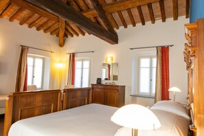 Una camera da letto con un letto grande, una testiera in legno, una cassettiera, uno specchio e un soffitto con travi a vista.