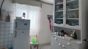 A kitchen with a refrigerator, a cabinet with glass doors, and a hanging light fixture. - Comfortable house with terrace a stone's throw from the sea in mild climate location (Villapiana Lido)