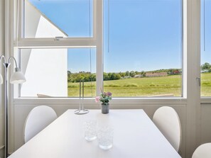 A room with a large window, a table with two glasses, a lamp, and a vase with flowers. - "Kirsti" - 300m from the sea by Interhome (Allinge)