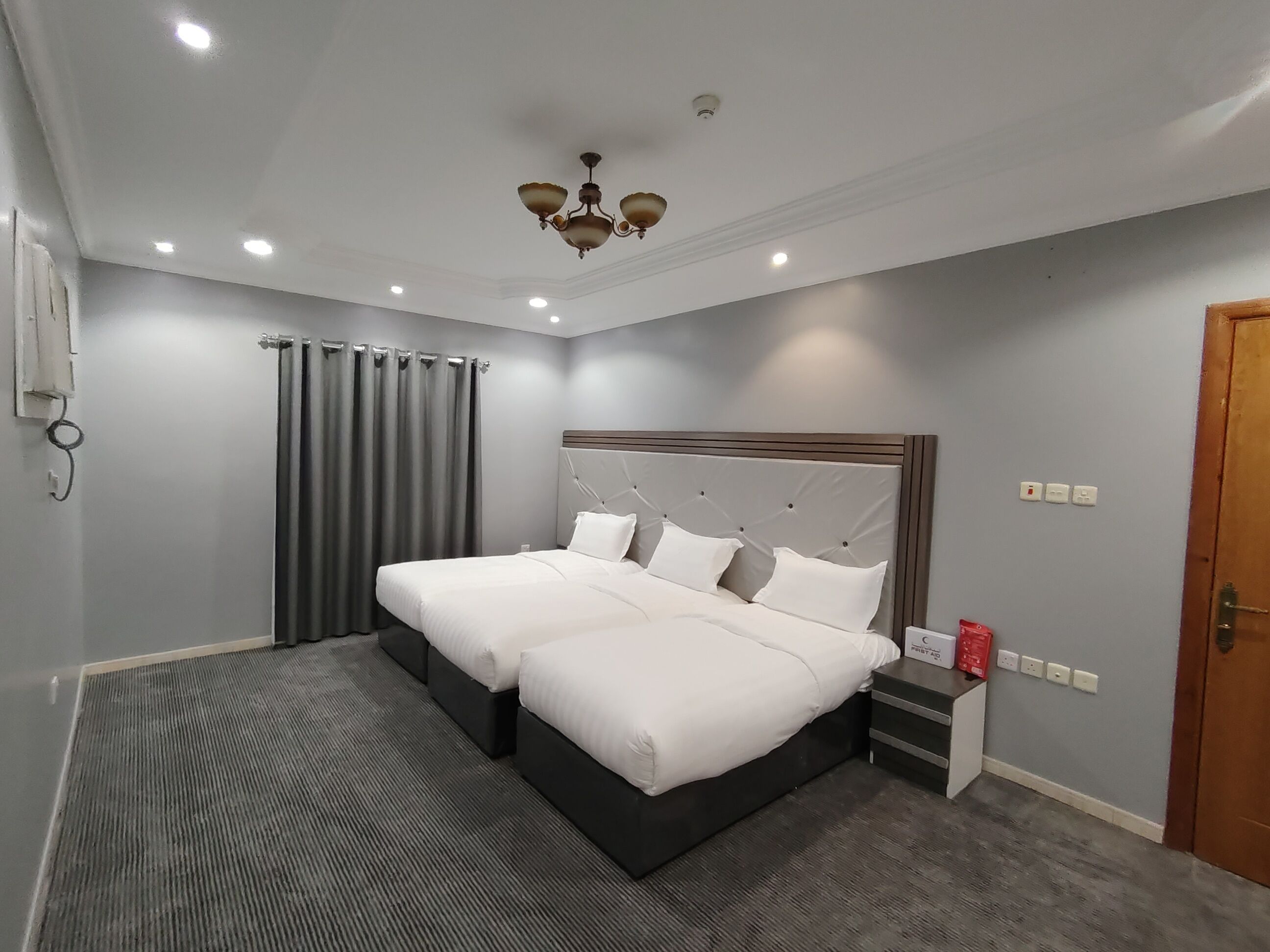 Una habitación de hotel moderna con una cama grande, una mesita de noche y una lámpara en el techo.