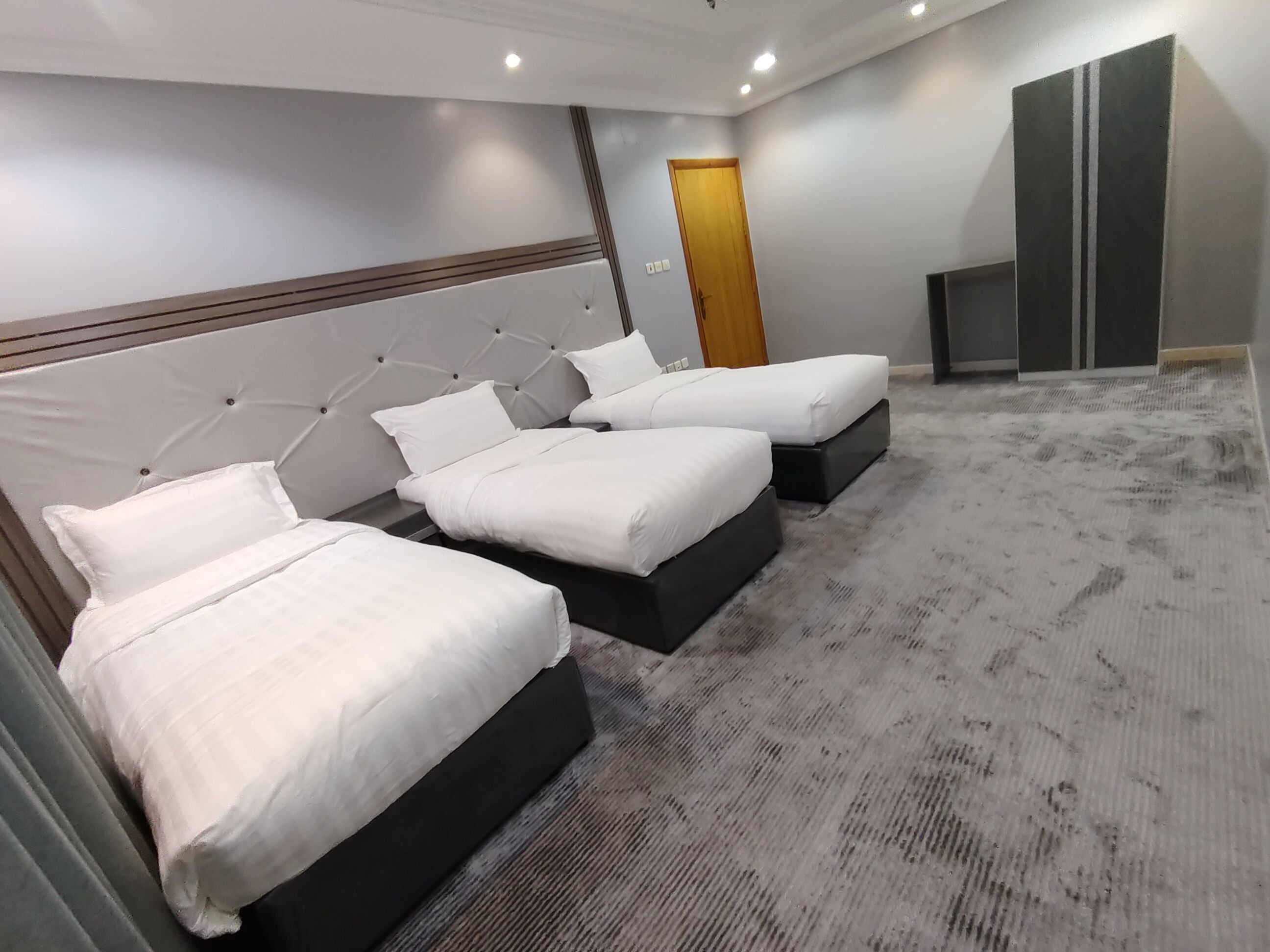 A hotel room with three beds, a television, and a door.