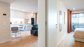 Ein modernes Hotelzimmer mit Holzboden, einem Bett, einem großen Fenster mit Vorhängen und Blick nach draußen.