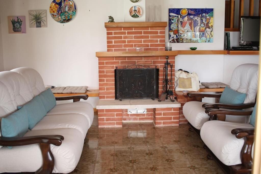 A living room with two beige sofas, a brick fireplace, and a television on a wooden stand.