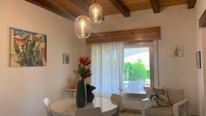 Ein Essbereich mit einem runden Tisch und Stühlen, einer Vase mit Blumen und einem Bild einer Kaktee an der Wand.