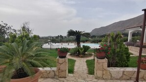 Ein steinbelagter Weg führt zu einem Poolbereich mit Topfpflanzen und Blick auf eine Berglandschaft.