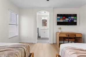 Une chambre d’hôtel moderne équipée d’une télévision permettant d’accéder à diverses applications de diffusion en continu, d’une table à manger en bois et offrant une vue sur la cuisine.