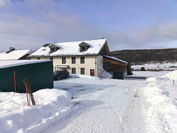 Una casa de dos pisos amb un teulat cobert de neu, un garatge i una entrada.