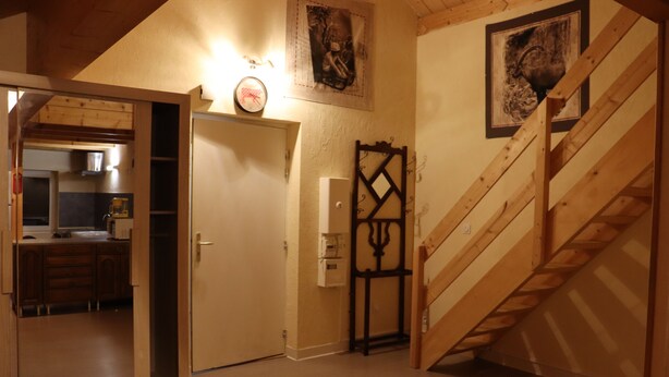 A kitchen with wooden cabinets, a refrigerator, and a coffee maker. There is a door leading to another room and a staircase with wooden railings. - chalet-style apartment, 5 minutes from the ski slopes (Les Rousses)