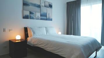 A bedroom with a bed, two bedside lamps, a nightstand, and a wall-mounted artwork.
