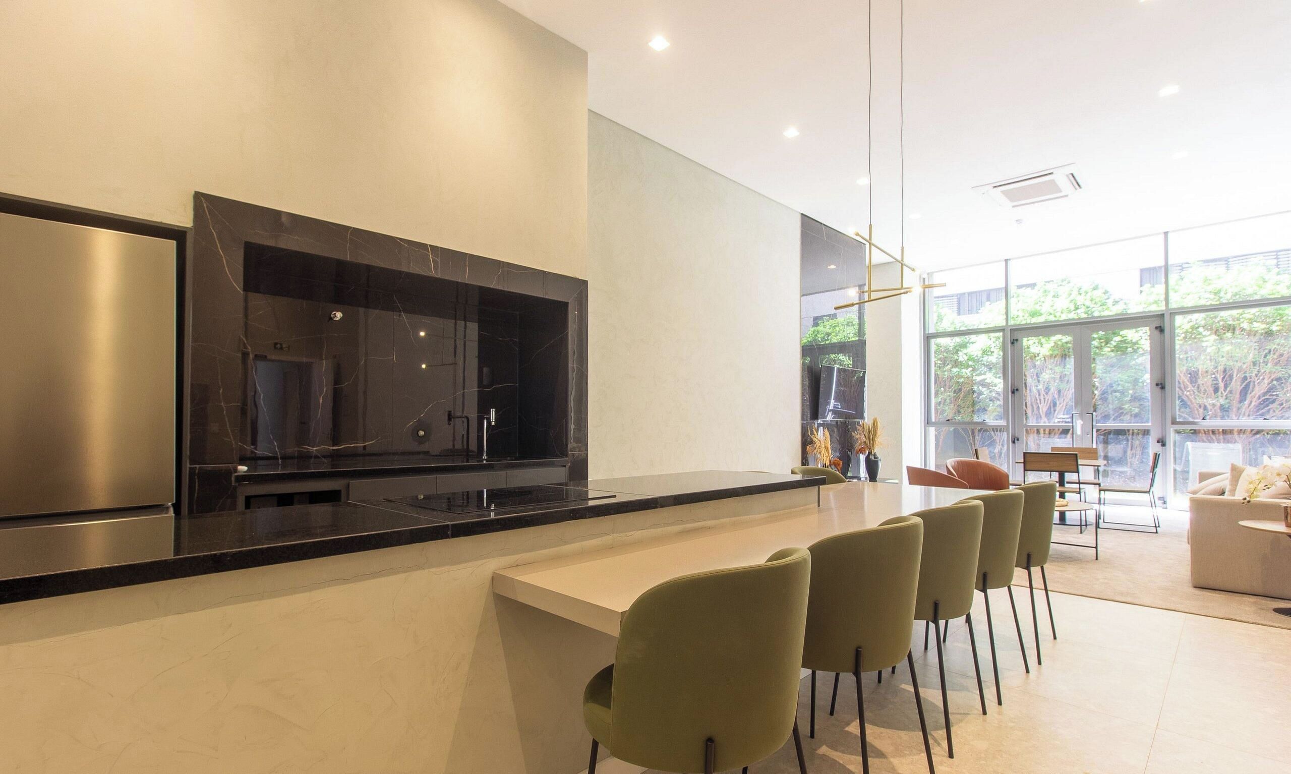 Una cocina moderna con una isla grande, asientos tipo bar y un comedor con vistas.