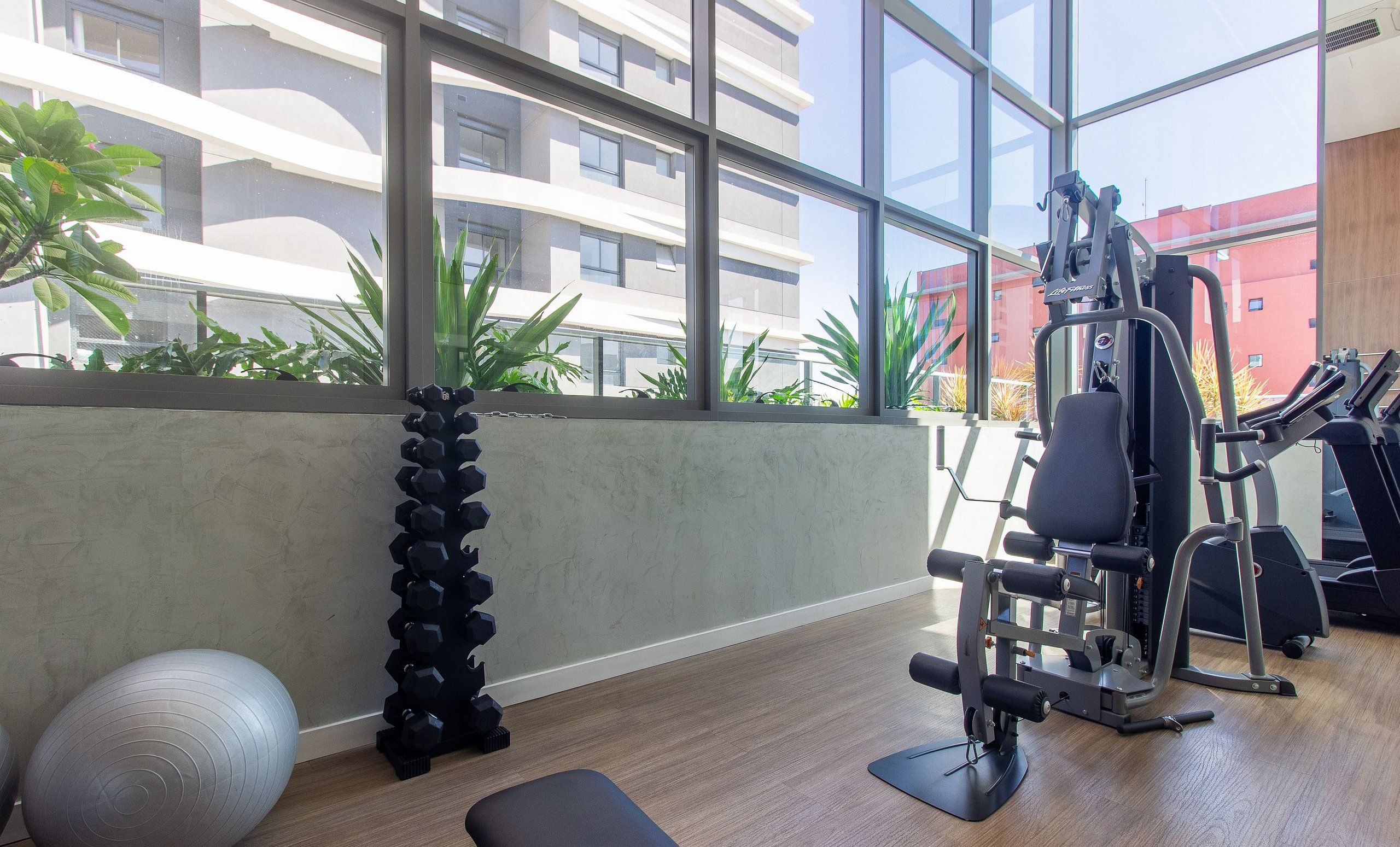 A gym with exercise equipment, a yoga mat, and a dumbbell rack.