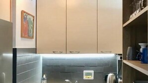 Een kleine keuken met een vaatwasser, een spoelbak en een betegelde spatwand.
