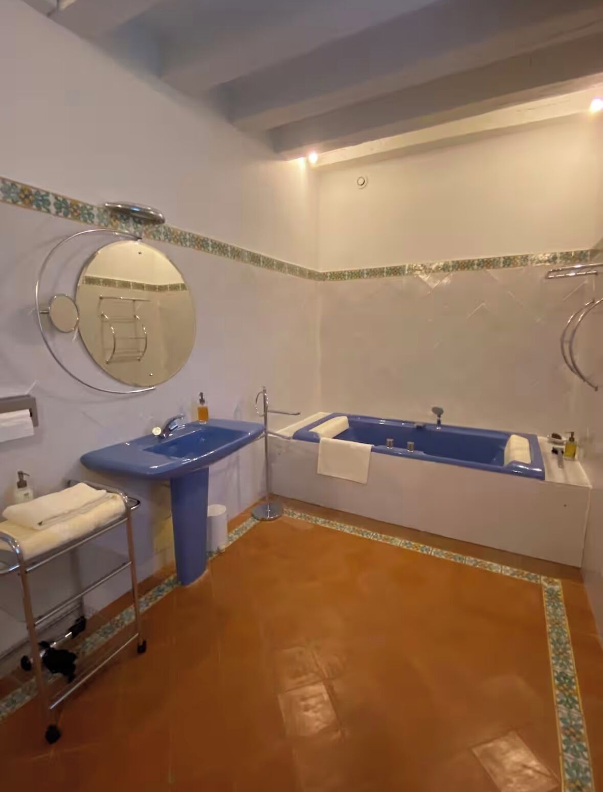 A bathroom with a blue sink, a large mirror, and a bathtub.
