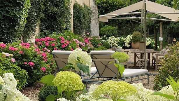 A garden with outdoor seating, a pergola, and a building with a beige facade. - Suite d'hôtes - Domaine de Poulaines (Poulaines)