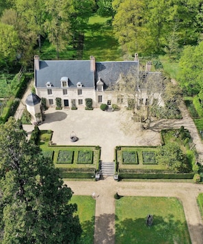 A large, symmetrical building with a central courtyard, surrounded by manicured gardens and trees. - Suite d'hôtes - Domaine de Poulaines (Poulaines)