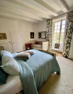 A bedroom with a bed, a chair, a window with curtains, and a door. - Suite d'hôtes - Domaine de Poulaines (Poulaines)