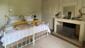A bedroom with a bed, bedside lamps, a fireplace, and a mirror. - Suite d'hôtes - Domaine de Poulaines (Poulaines)