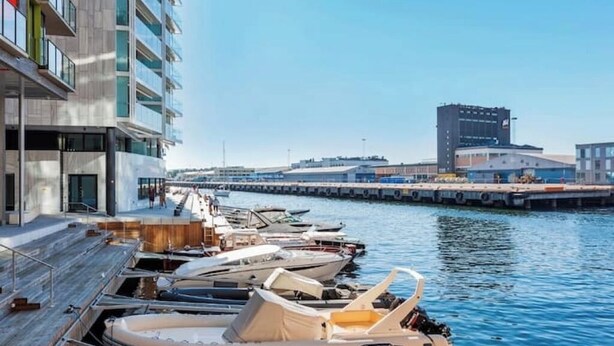 A marina with boats docked, a modern building with balconies, and a clear sky. - Modern apartment in the heart of Oslo with balcony (Oslo)