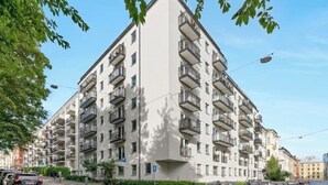 A multi-story residential building with balconies, a parking area, and a clear sky. - Modern apartment in the heart of Oslo with balcony (Oslo)