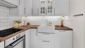 A modern kitchen with white cabinetry, a black induction cooktop, and a built-in oven. - Modern apartment in the heart of Oslo with balcony (Oslo)